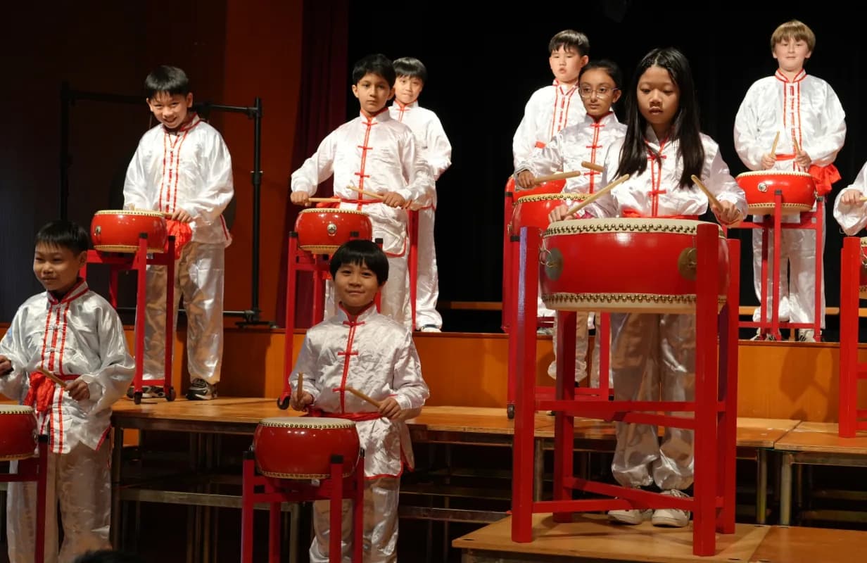 毕架山小学学生身穿中式表演服在舞台上击打中国大鼓