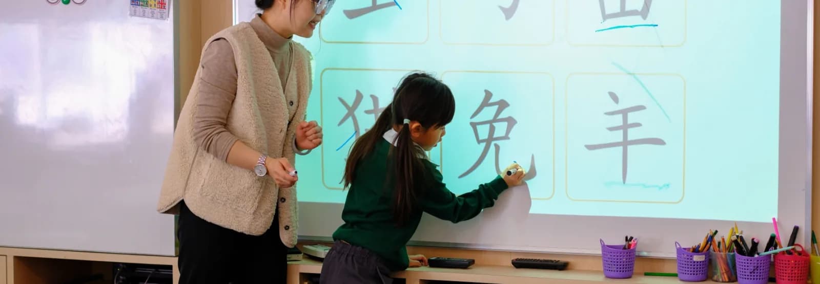 山顶小学学生在老师旁边用电子白板练写汉字