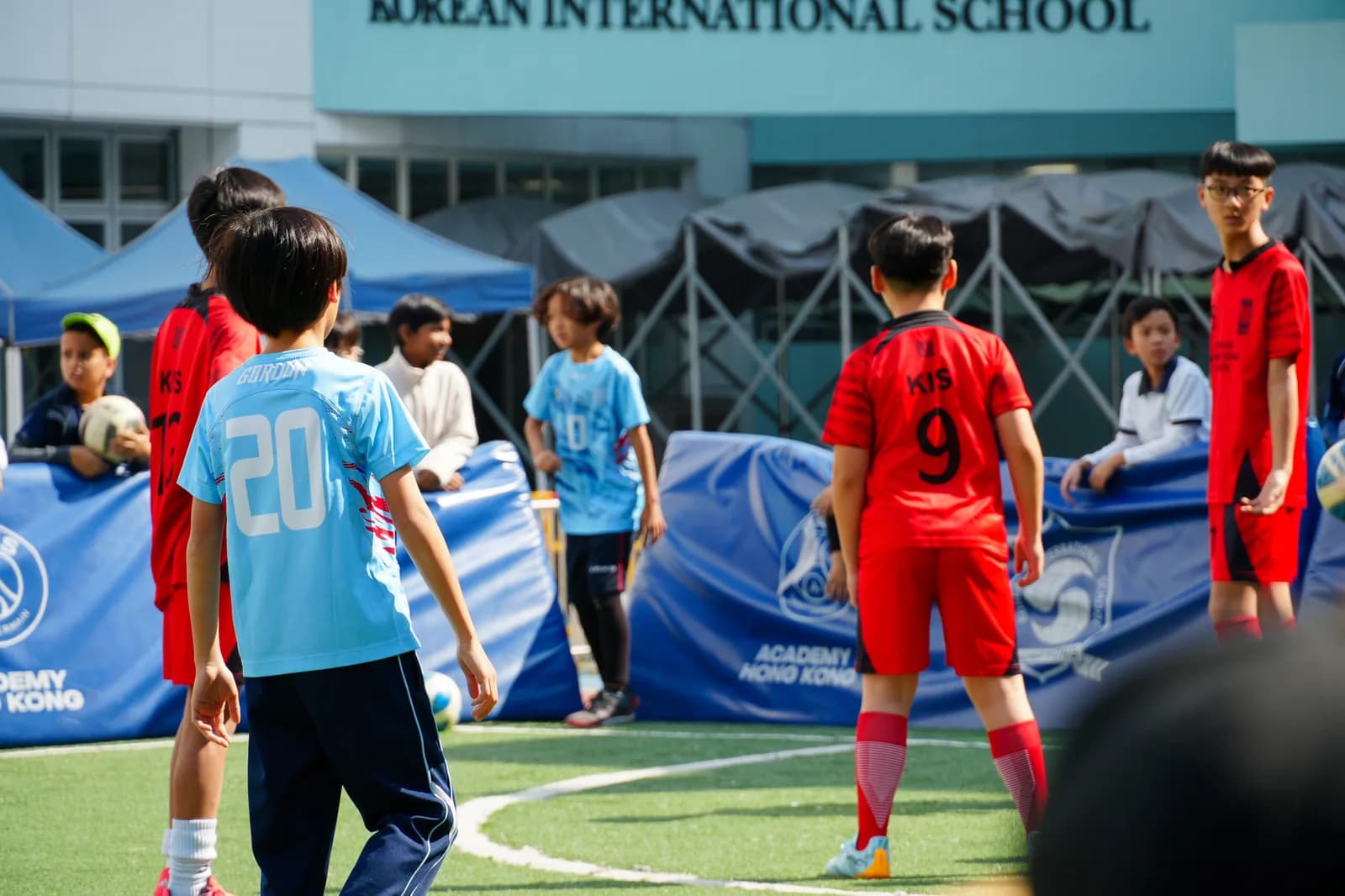 韩国国际学校西湾河校园足球场，学生在校舍前踢球