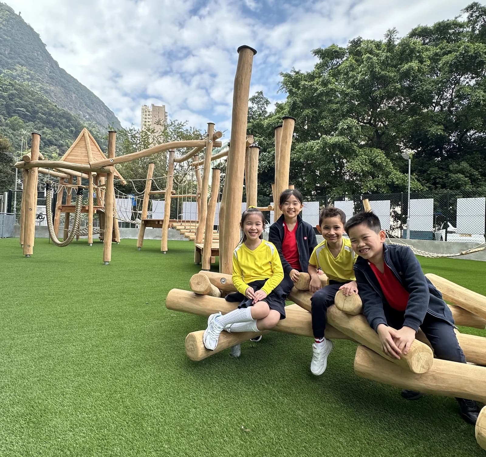 己连拿小学草地操场上的木结构攀爬架,背后是半山住宅和山景