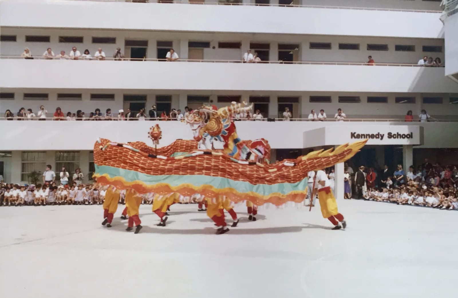 坚尼地小学沙湾径校舍前的操场上舞龙表演,师生在各层走廊观看