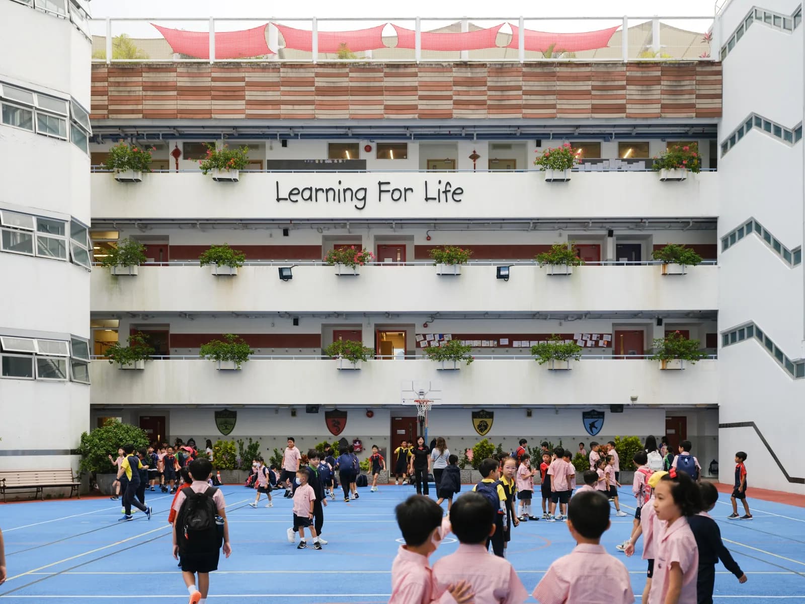 沙田小学教学楼外墙写着 Learning For Life,学生在蓝色球场上活动